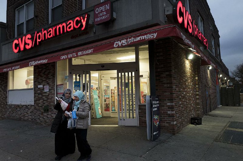 CVS Health customers  leave a pharmacy in Brooklyn, N.Y., on Sunday. The pharmacy chain has reportedly agreed to buy insurance giant Aetna.