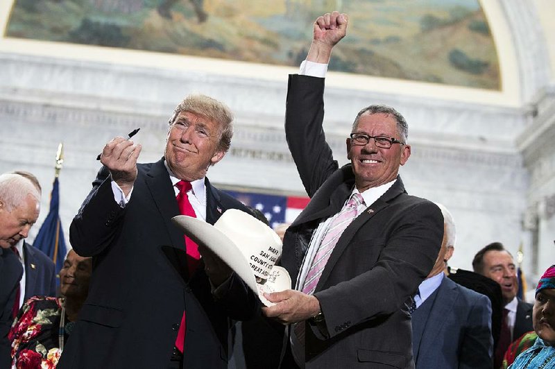 President Donald Trump signs the hat of Bruce Adams, chairman of the San Juan County Commission, after speaking Monday in Salt Lake City about his decision to shrink the size of the Bears Ears and Grand Staircase-Escalante national monuments.