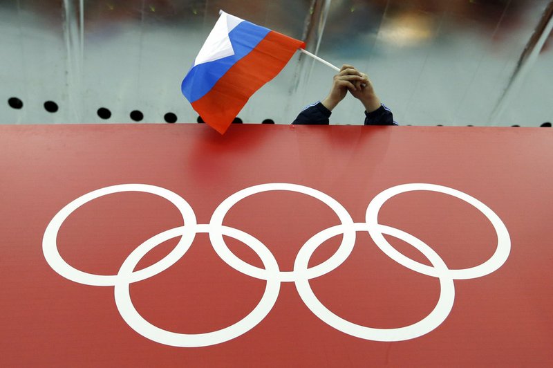 In this Feb. 18, 2014, file photo, a Russian skating fan holds the country's national flag over the Olympic rings before the start of the men's 10,000-meter speedskating race at Adler Arena Skating Center during the 2014 Winter Olympics in Sochi, Russia. 