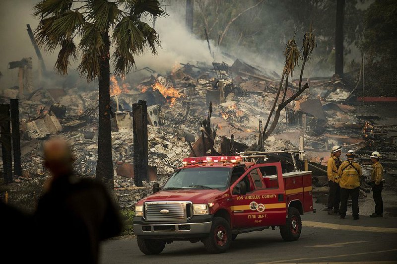 Firefighters work around the remains of an apartment complex in Ventura, Calif., that was destroyed Tuesday by a wildfire. The fire grew to more than 70 square miles in a matter of hours, officials said. 