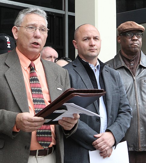 The Sentinel-Record/Richard Rasmussen FIGHTING CITY HALL: Doug Jones, left, president of the Watchmen of Garland County, reads a statement Tuesday in front of City Hall announcing the Concerned Citizens Coalition's intent to gather signatures in support of a referendum against the pending water rate increase. District 9 Justice of the Peace Matt McKee, center, and Difference Makers of Hot Springs President Willie Wade Jr. also spoke against the rate increase.