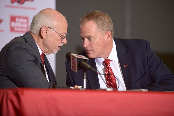 Joe Steinmetz (left), chancellor of the University of Arkansas, shakes hands Wednesday, Dec. 6, 2017, with Hunter Yurachek after Yurachek was introduced as the new director of athletics at the University of Arkansas during a news conference in the Fowler Family Baseball and Track Indoor Training Center in Fayetteville.
