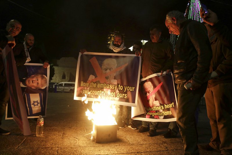 Palestinian burn a poster of the U.S. President Donald Trump during a protest in Bethlehem, West Bank, on Tuesday, Dec. 6, 2017.