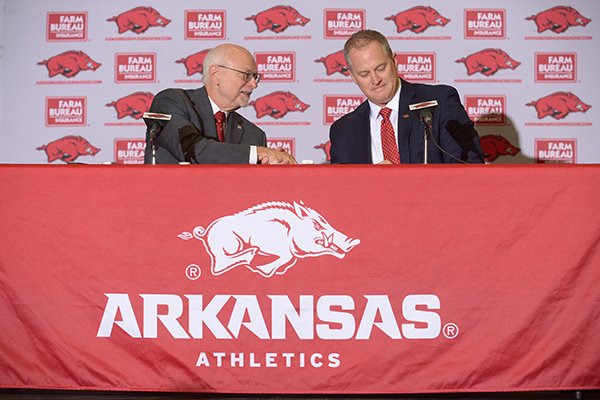 University of Arkansas chancellor Joseph Steinmetz (left) shakes hands with Hunter Yurachek, the newly announced athletic director Wednesday, Dec. 6, 2017 at a press conference in Fayetteville. 