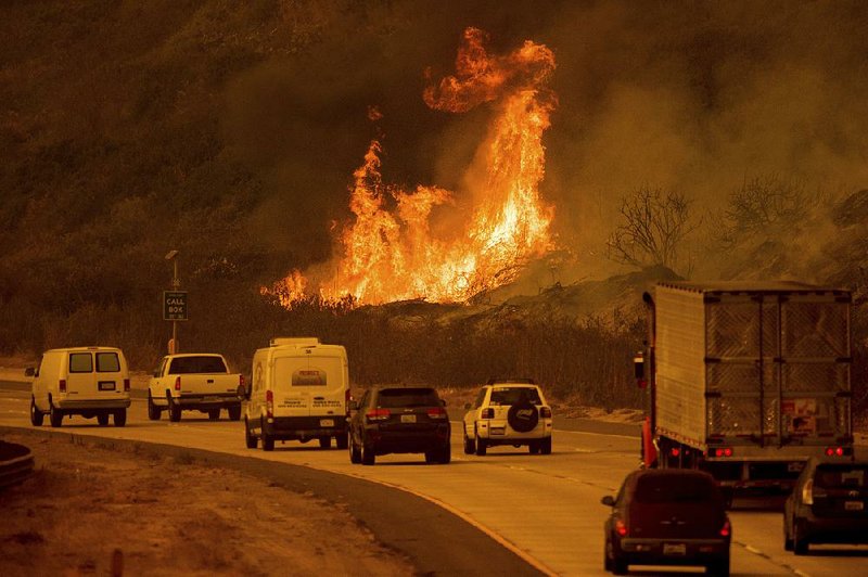 Flames from a wildfire leap above traffic Wednesday on California 101 north of Ventura, Calif. 