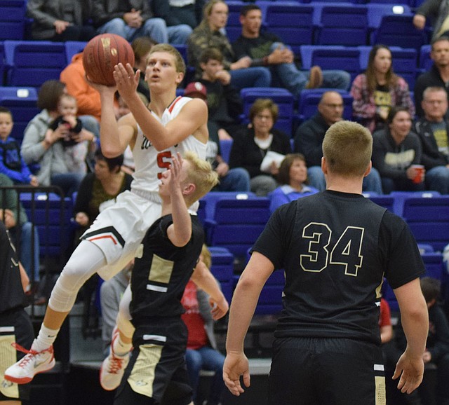 RICK PECK SPECIAL TO MCDONALD COUNTY PRESS McDonald County's Boston Dowd goes up and around Neosho's Kaden King for a basket during the Wildcats 54-49 win on Dec. 1 in the 71st Carthage Invitational Boys Basketball Tournament.