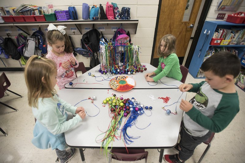 NWA Democrat-Gazette/SPENCER TIREY Kindergartners Analie Dryer (From Left) Kendall Langley, Kathryn Cooksey and Blake Harris work on making jingle bell necklace in Cristine Eubanks' class at Thomas Jefferson Elementary in Bentonville. This is the third year students have done the project to raise money for students in need at the school. Last year the project raised about $1,100.