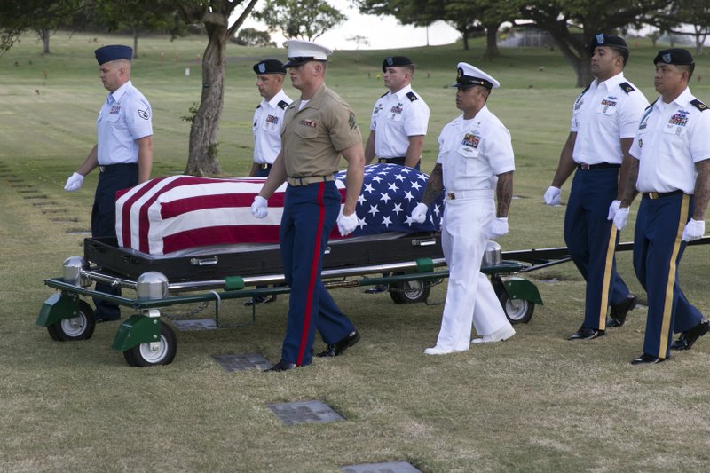 In this July 27, 2015 file photo, military pallbearers escort the exhumed remains of unidentified crew members of the USS Oklahoma killed in the 1941 bombing of Pearl Harbor that were disinterred from a gravesite at the National Memorial Cemetery of the Pacific in Honolulu. The military says it has identified 100 sailors and Marines killed when the USS Oklahoma capsized during the Japanese bombing of Pearl Harbor 76 years ago. The milestone comes two years after the Defense POW/MIA Accounting Agency dug up nearly 400 sets of remains from a Hawaii to identify the men who have been classified as missing since the war. 