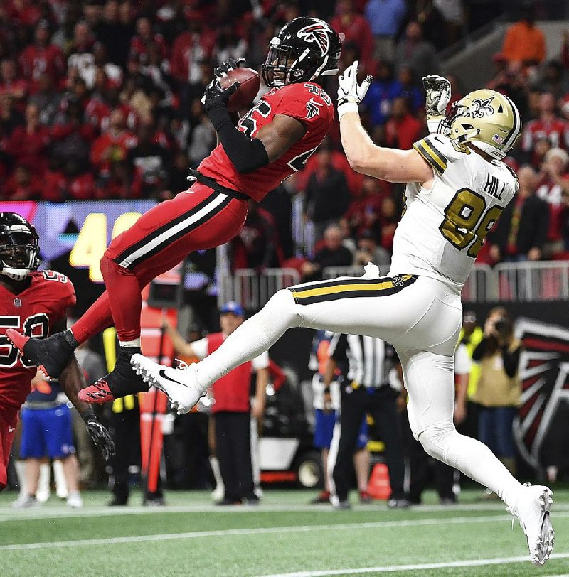 Atlanta middle linebacker Deion Jones (left) intecepts a pass in the end zone intended for New Orleans tight end Josh Hill that preserved the Falcons’ 20-17 victory over the Saints on Thursday at Mercedes-Benz Stadium in Atlanta.