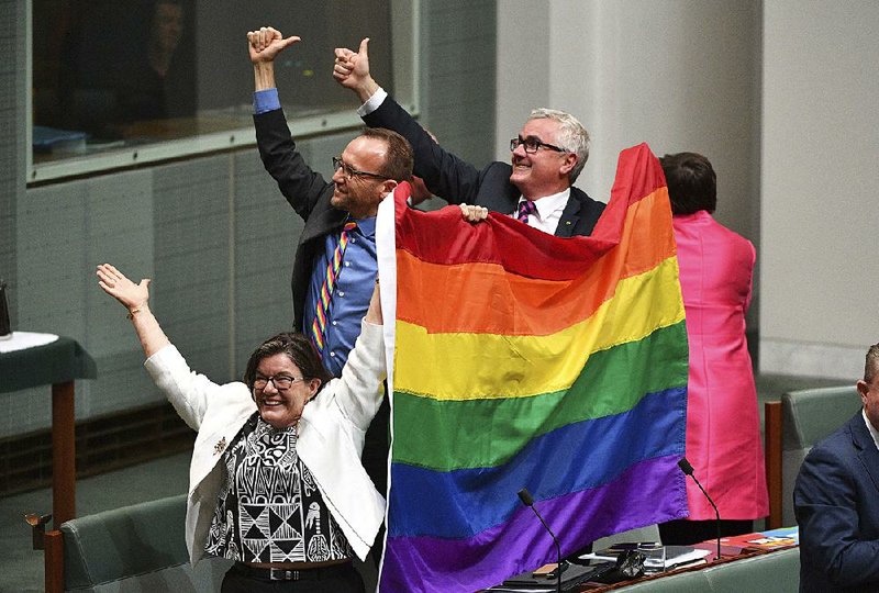 Members of Australia’s Parliament (from  left) Cathy McGowan, Adam Brandt and Andrew Wilkie celebrate the House of Representatives’ passage Thursday of the same-sex marriage bill.
