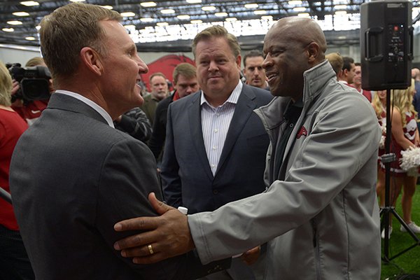 Arkansas football coach Chad Morris, left, is greeted by Arkansas basketball coach Mike Anderson, right, while agent Jimmy Sexton looks on following a news conference Thursday, Dec. 7, 2017, in Fayetteville. 