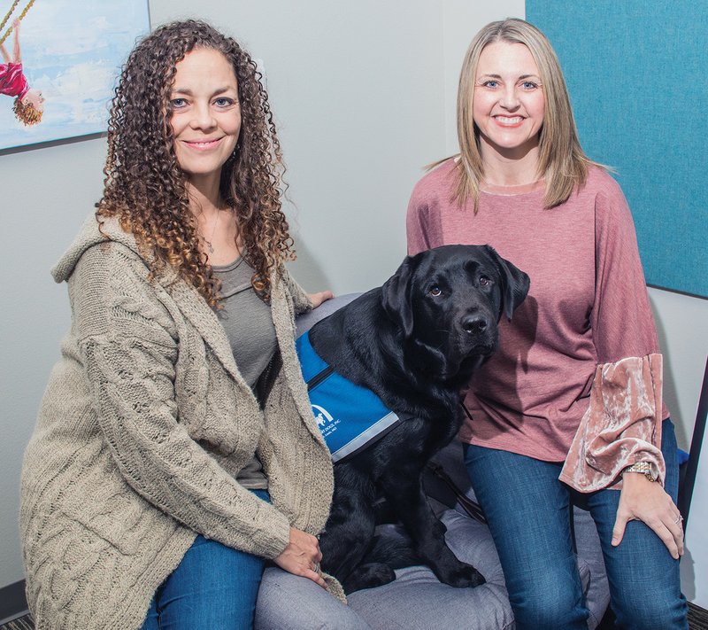 Felicia Patten, left, and Robin Connell pose with Jake, an 83-pound English Labrador, who will help calm the fears of children who come to the Child Safety Center of White County in Searcy. Patten is a forensic interviewer and Jake’s secondary handler; Connell is executive director and Jake’s primary handler. It was a two-year process to get Jake through the nonprofit Courthouse Dogs Foundation, and he was trained at Support Dogs Inc. in St. Louis, Mo.