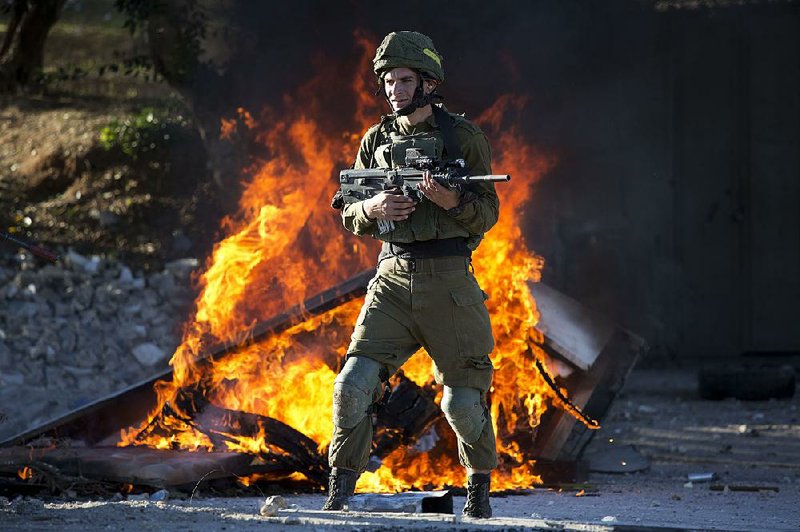 An Israeli soldier stays on guard Friday during clashes with Palestinian protesters in the West Bank city of Nablus.