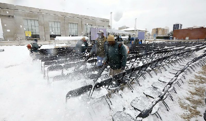 Workers clear rare heavy snow Friday in Jackson, Miss., from chairs set up for today’s dedication of the Museum of Mississippi History and the Mississippi Civil Rights Museum. Many in the state’s black community, despite waiting decades for a civil-rights museum, are planning to skip the event because President Donald Trump will be attending.