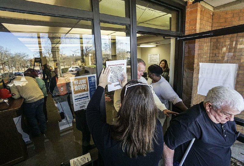 Marisha DiCarlo, director of communications for the state Department of Health, puts up a sign Friday morning outside the vital-records office indicating no birth certificates could be issued. By noon, the office was back to issuing the certificates after an order from Gov. Asa Hutchinson.