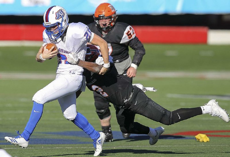 Arkadelphia quarterback Cannon Turner tries to break a tackle by Warren’s Psavian Person during Saturday’s Class 4A championship game at War Memorial Stadium in Little Rock. Turner passed for 281 yards and was named the game’s MVP.