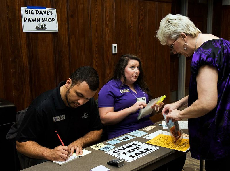 A woman makes a transaction at the pawnshop booth during last week’s poverty simulation at the University of Central Arkansas in Conway. The event was intended to help people better understand poverty.