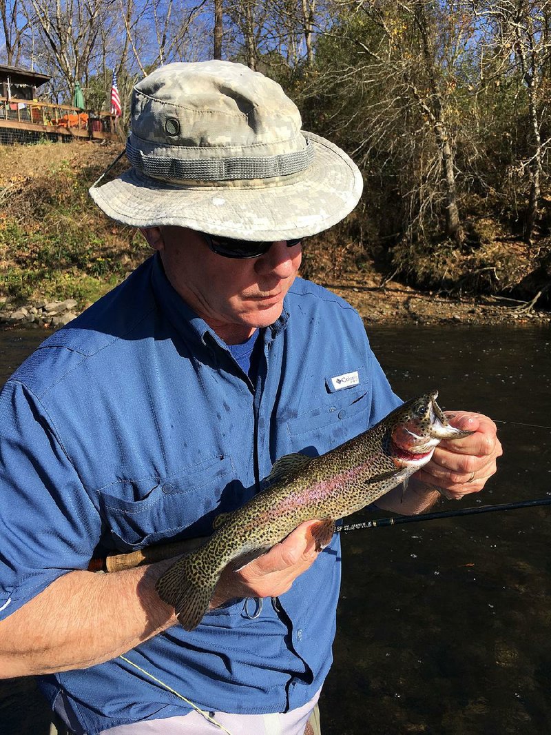 Rusty Pruitt of Bryant admires a rainbow trout he caught last week on the Little Red River near Heber Springs.