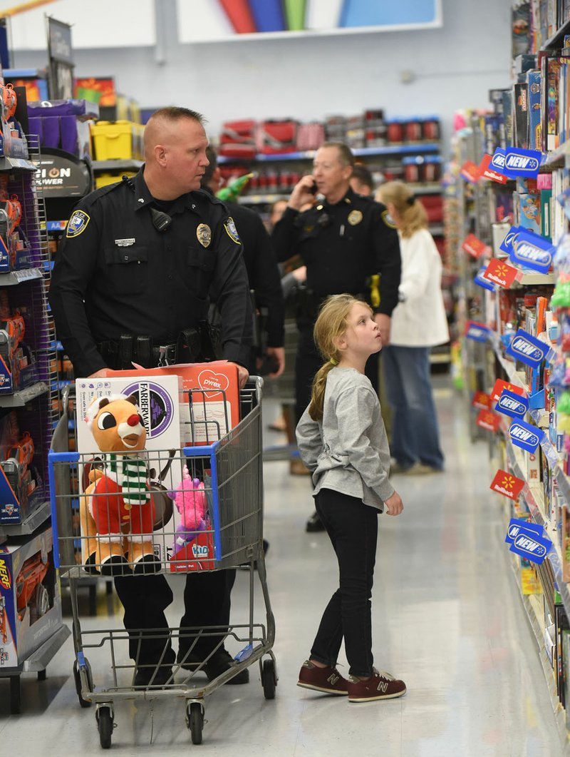 Cpl. Kenneth Trimberger with the Bentonville Police Department helps Tori Creekmore, 8, select Christmas gifts Dec. 5 during Shop with a Cop in Bentonville.