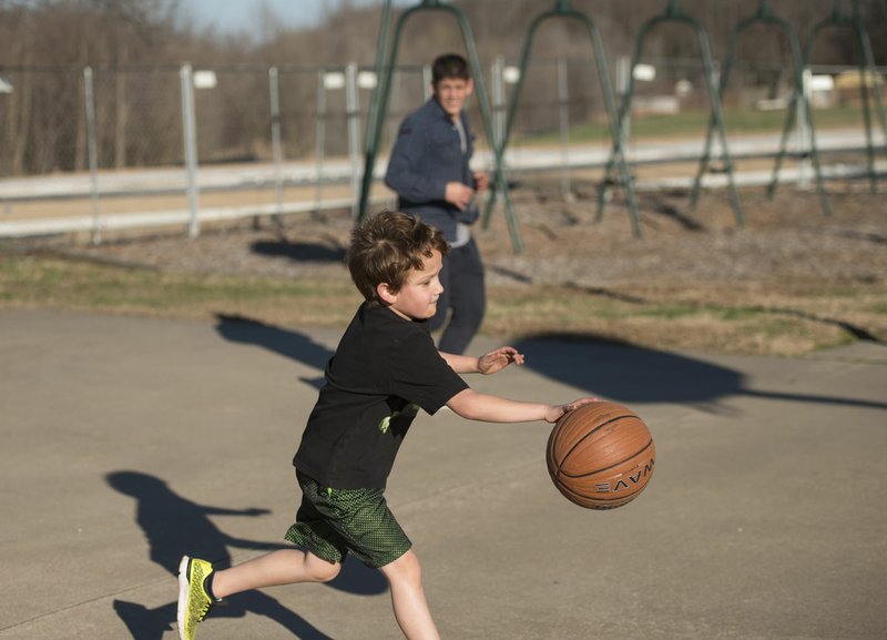 Nelson Contreras of Garfield helps son Noah Contreras, 7, work on his basketball skills Sunday at Maple Grove Park in Rogers. The park is slated for renovation including a restroom, paved parking lot and a tunnel that takes pedestrians who are headed toward the Railyard Bike Park under the road. The work is set to be completed this spring.