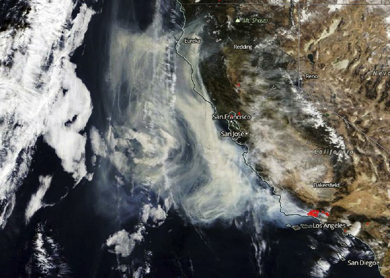 This satellite image provided by NASA shows smoke from wildfires near Los Angeles in Southern California blowing out toward clouds over the Pacific Ocean on Monday.