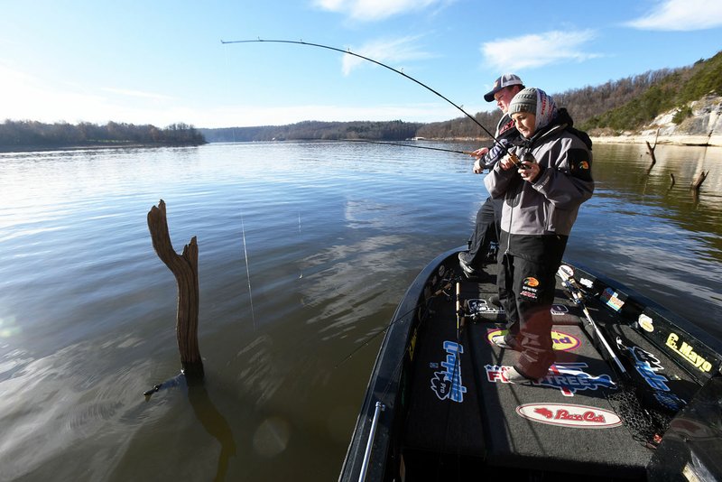 Tiffany Usrey of Springdale catches a crappie near Horseshoe Bend park on Nov. 24 while she and her husband, Payton (left) fish at Beaver Lake. The couple cast jigs around submerged timber and docks to catch several crappie.