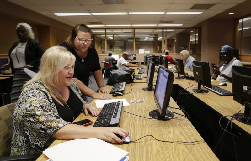 In this Thursday, July 27, 2017, photo, Cheryl Bast of Omaha, left, is accompanied by her daughter Liz Pierson as she works on an application for a position with Omaha Public Schools during a job fair held in Omaha, Neb. On Monday, Dec. 11, 2017, the Labor Department reports on job openings and labor turnover for October. 