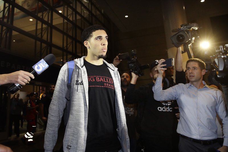 FILE - In this Nov. 14, 2017, file photo, UCLA basketball player LiAngelo Ball is surrounded by reporters and photographers as he leaves Los Angeles International Airport in Los Angeles. A basketball club from Lithuania says it has signed LiAngelo and LaMelo Ball to pro contracts, making them ineligible for college basketball. The Prienai-Birstonas Vytautas club, which plays in the Lithuanian league, says the brothers will report to the club "in early January," in a website statement. (AP Photo/Jae C. Hong, File)