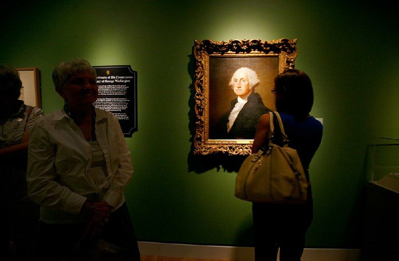 A visitor in 2013 views a portrait of George Washington at Crystal Bridges Museum of American Art, which is in one of the galleries that will shut temporarily.