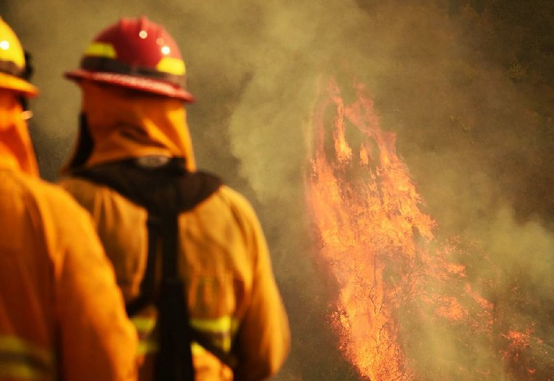 Firefighters monitor flames as pockets of vegetation ignite Wednesday in Montecito, Calif. 