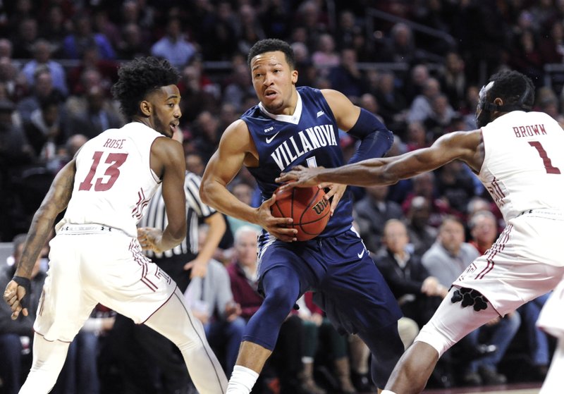 Villanova's Jalen Brunson (1) drives to the basket against Temple's Quinton Rose (13) and Josh Brown (1) during the first half an NCAA college basketball game, Wednesday, Dec. 13, 2017, in Philadelphia. (AP Photo/Michael Perez)