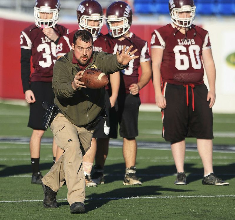 Josh Baker, a Montgomery County deputy sheriff and former Mount Ida player, punts the ball as he helps the Lions during Thursday’s practice at War Memorial Stadium in Little Rock.