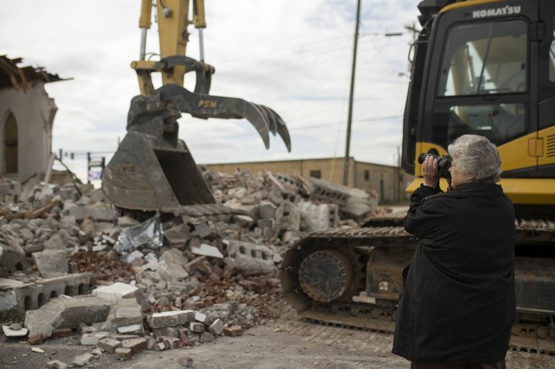 Brenda Pianalto of Springdale takes pictures Thursday before a bulldozer continues demolition on the old St. Joseph Catholic Church building in Tontitown. She said she was baptized and had her First Communion at the old building.