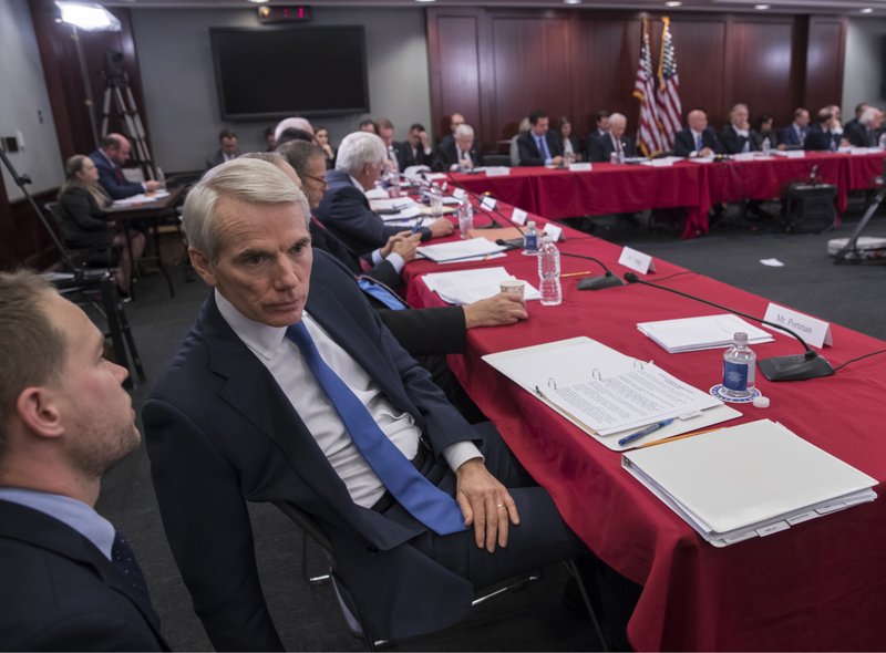 Sen. Rob Portman, R-Ohio, a member of the tax-writing Senate Finance Committee, confers with an aide as tax bill conferees gather to work on the sweeping GOP plan, on Capitol Hill in Washington, Wednesday, Dec. 13, 2017. 