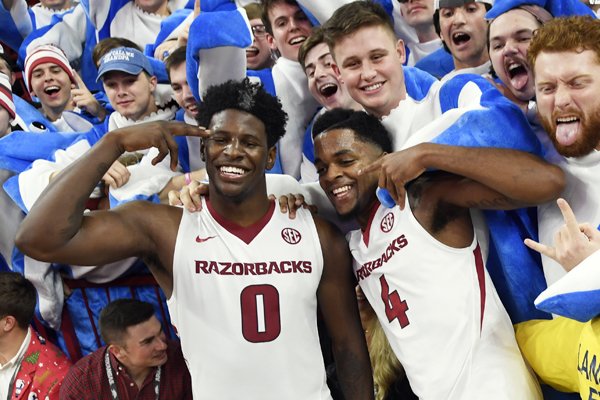 Arkansas players Jaylen Barford (0) and Daryl Macon (4) celebrate with fans after beating Minnesota after the second half of an NCAA college basketball game Friday, Dec. 9, 2017 in Fayetteville, Ark. (AP Photo/Michael Woods)

