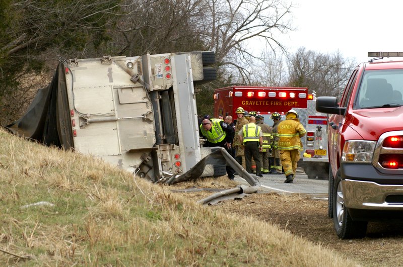 A police officer looks at the trailer brakes of an overturned tractor-trailer rig on Arkansas Highway 43 on Thursday morning following an accident which claimed the life of the driver and injured two others in a separate vehicle.