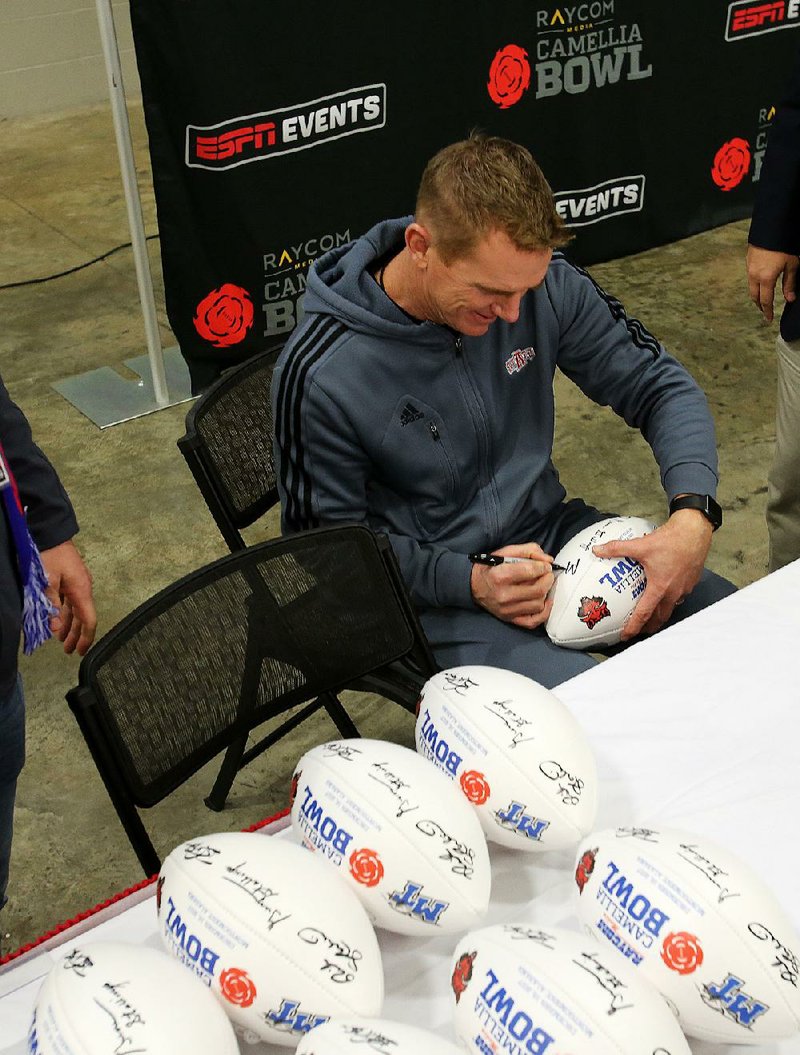 Arkansas State Coach Blake Anderson signs commemorative Camellia Bowl footballs Friday in Montgomery, Ala. The Red Wolves take on Middle Tennessee State tonight. 
