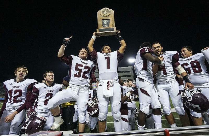 Foreman’s Corey Lovewell hoists the trophy after the Gators’ victory over Mount Ida in Friday night’s Class 2A championship game at War Memorial Stadium in Little Rock. 