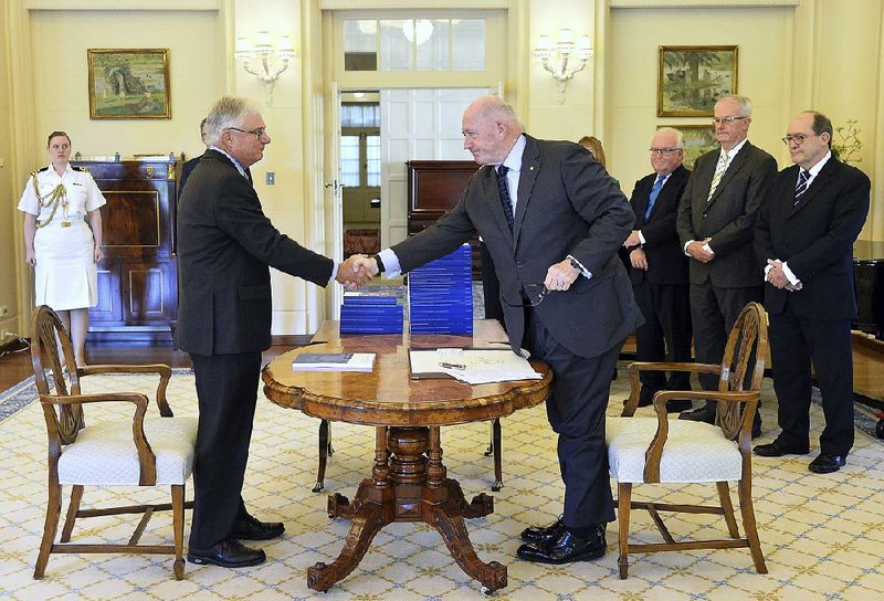 Peter McClellan (left), a member of the Royal Commission into Institutional Responses to Child Sexual Abuse, and Australian Governor General Peter Cosgrove mark with a handshake Friday’s release of the panel’s 17-volume report. 
