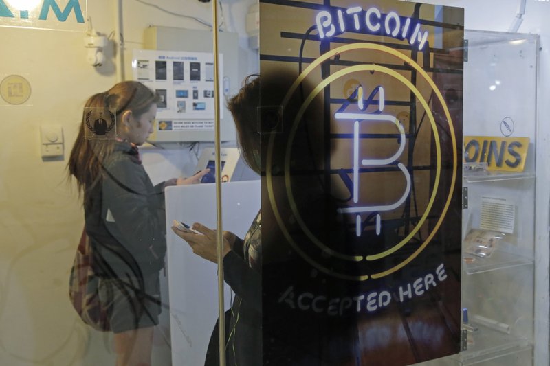 In this Dec. 8 file photo, people use a Bitcoin ATM in Hong Kong. The public’s intense interest in all things bitcoin, and efforts by entrepreneurs to fund their businesses with digital currencies, has begun to draw attention from regulators. (AP Photo/Kin Cheung, File)