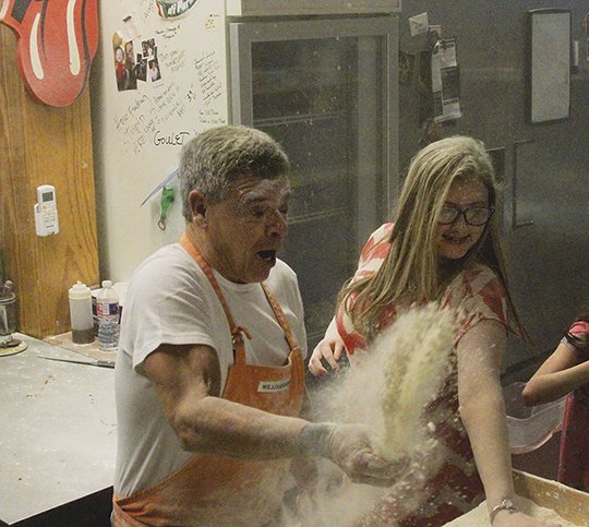 The Sentinel-Record/Grace Brown FLINGING FLOUR: Anthony Valinoti, left, owner of DeLuca's Pizzeria and Sarah Gresham, 16, of Stuttgart, participate in a flour fight during the Shop with a Sheriff event at DeLuca's Pizzeria on Sunday. Valinoti invited the children back into the kitchen were they "made it snow" by slinging flour at one another.