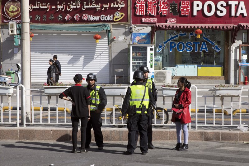 In this Nov. 3, 2017 photo, Chinese police officers question passerby along the roadside in Hotan in western China's Xinjiang region. Authorities are using detentions in political indoctrination centers and data-driven surveillance to impose a digital police state in the region of Xinjiang and its Uighurs, a 10-million strong, Turkic-speaking Muslim minority Beijing fears could be influenced by extremism. (AP Photo/Ng Han Guan)