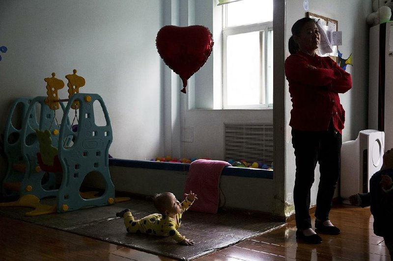 A child reaches toward an aide at a foster home outside Beijing that’s operated by the New Hope Foundation, which provides care for babies with deformities that can be corrected by surgery. Chinese families sometimes abandon children with medical problems because of high costs and rules restricting couples to two children. 
