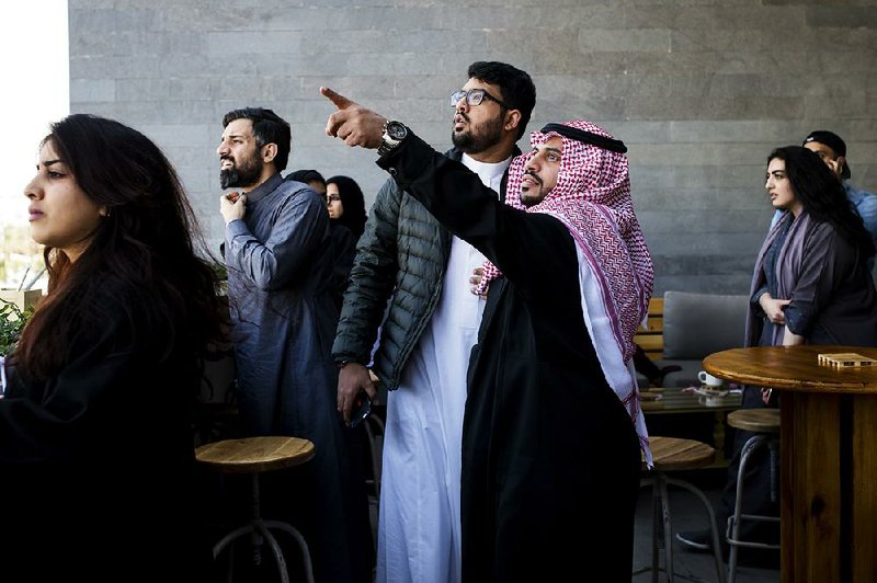 Customers at a coffee shop in Riyadh, Saudi Arabia, look at smoke rising after a loud boom Tuesday, apparently from an intercepted missile fired from Yemen. 