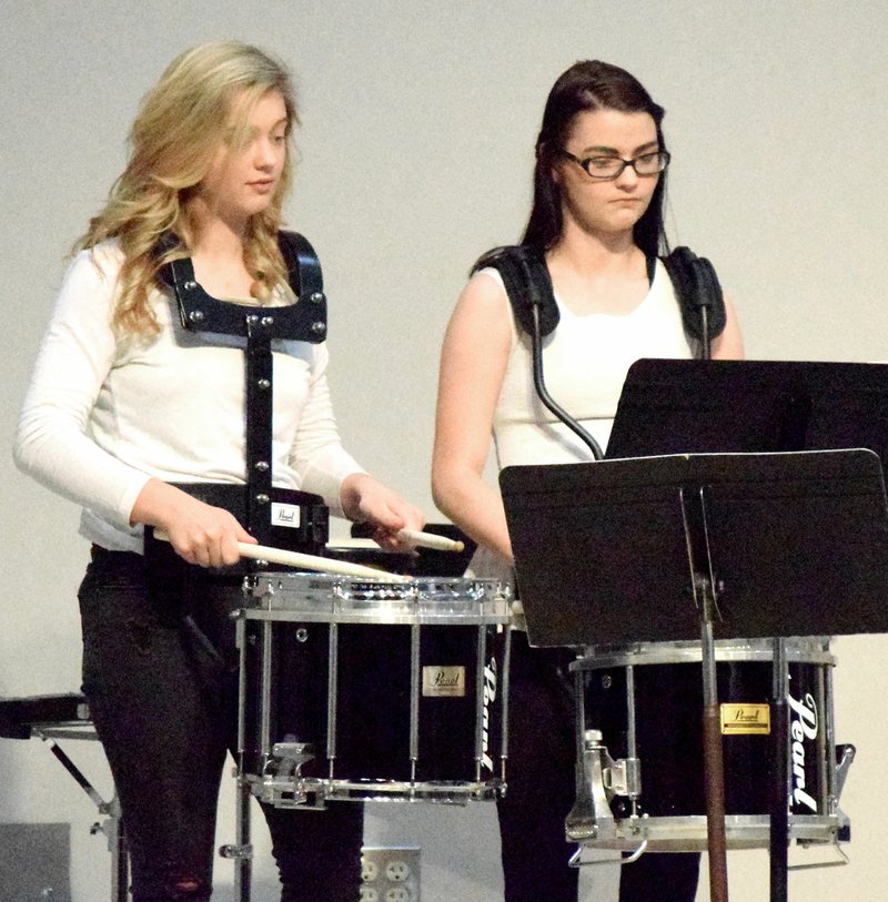 Westside Eagle Observer/MIKE ECKELS Alexis Patterson (left) and Kaitlyn Smith don their marching band snare drums to play "Three More Christmas Parades" during the Decatur Schools' winter concert in the cafeteria at Northside Elementary in Decatur Dec. 13. Both Patterson and Smith had performed this same piece during the Decatur Christmas Parade five days earlier with the marching band.