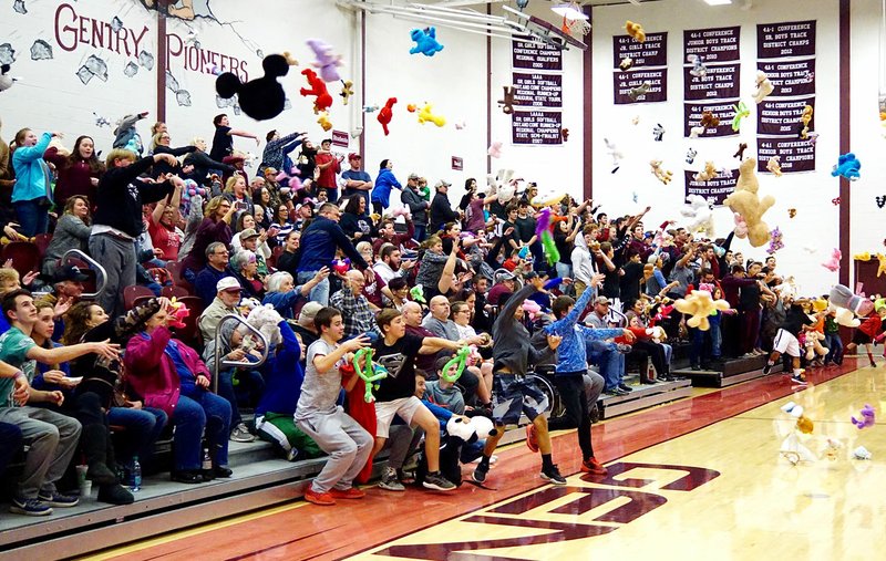 Westside Eagle Observer/RANDY MOLL Stuffed animals and toys fly through the air during the Gentry High School girls' basketball game on Friday. Following the first score on the Lady Pioneers, those in the stands tossed toys to the floor of the basketball court to be delivered to the Northwest Arkansas Children's Shelter.