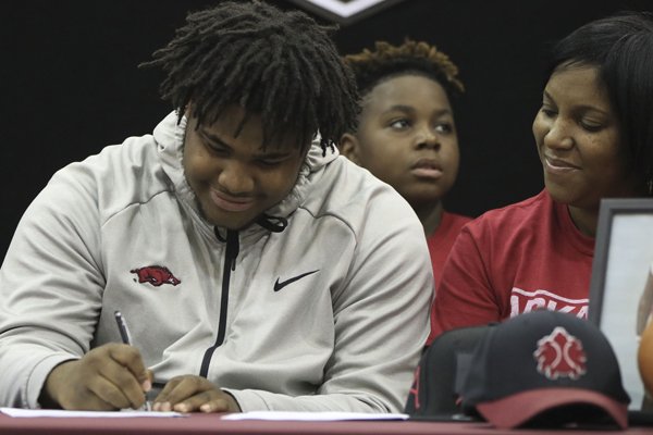 Fordyce High School senior Billy Ferrell (left) signs a letter of intent to play football at the University of Arkansas on Wednesday, Dec. 20, 2017, in Fordyce. Joining Ferrell was his mother Rene Stuckey (right) and younger brother, Malik Harden (center). 