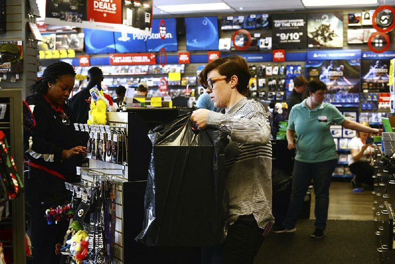 A GameStop employee assists a customer at a store in Kinston, N.C., on Black Friday. Researchers say the 2017 Christmas shopping season is on track to be the best in years. 