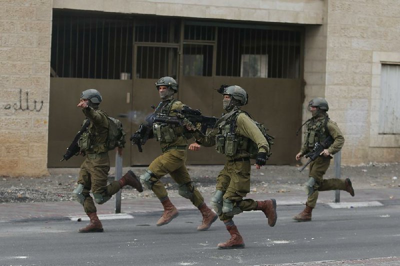 Israeli soldiers race to join a confrontation with Palestinian demonstrators Wednesday in the West Bank city of Bethlehem. 