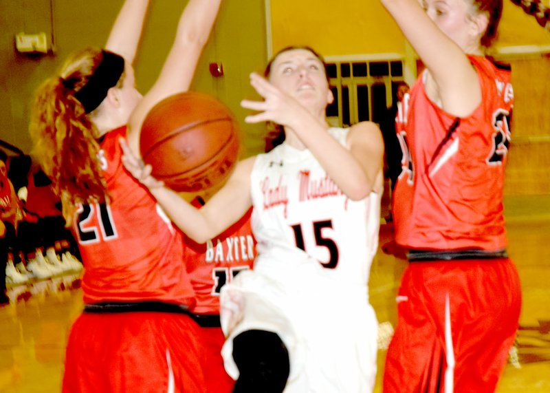 RICK PECK/SPECIAL TO MCDONALD COUNTY PRESS McDonald County's Ragan Wilson splits Baxter Springs' Abbey Underhill (21) and Delaney Barnes (24) while driving to the basket during the Lady Mustangs' 41-35 loss on Dec.14 at MCHS.